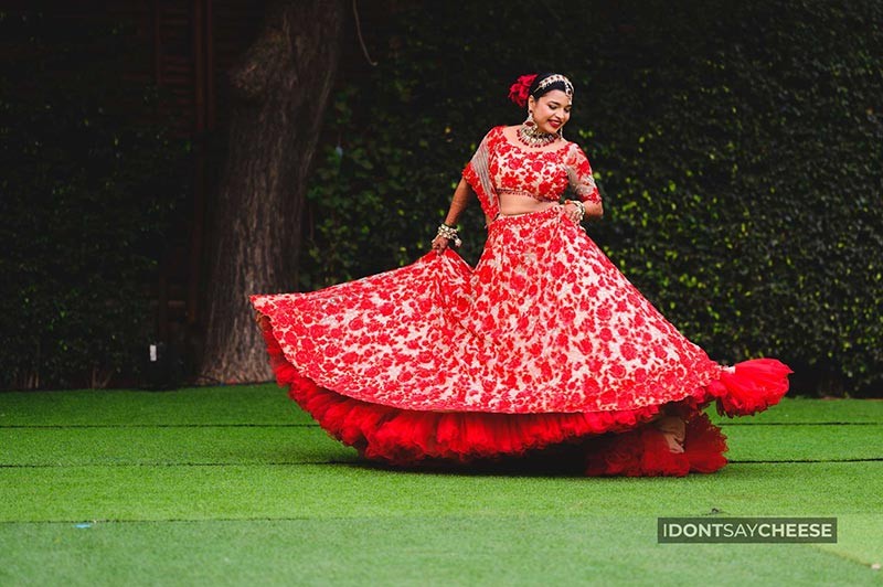 Bride posing solo outdoors in a twirling red outfit