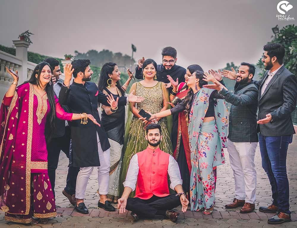 Group photograph of Deepanshu and Sonali with guests in vibrant outfits at their wedding celebration