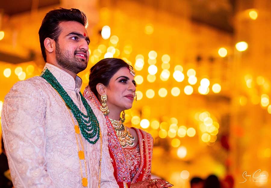 Groom celebrating during the baraat procession surrounded by colourful garlands