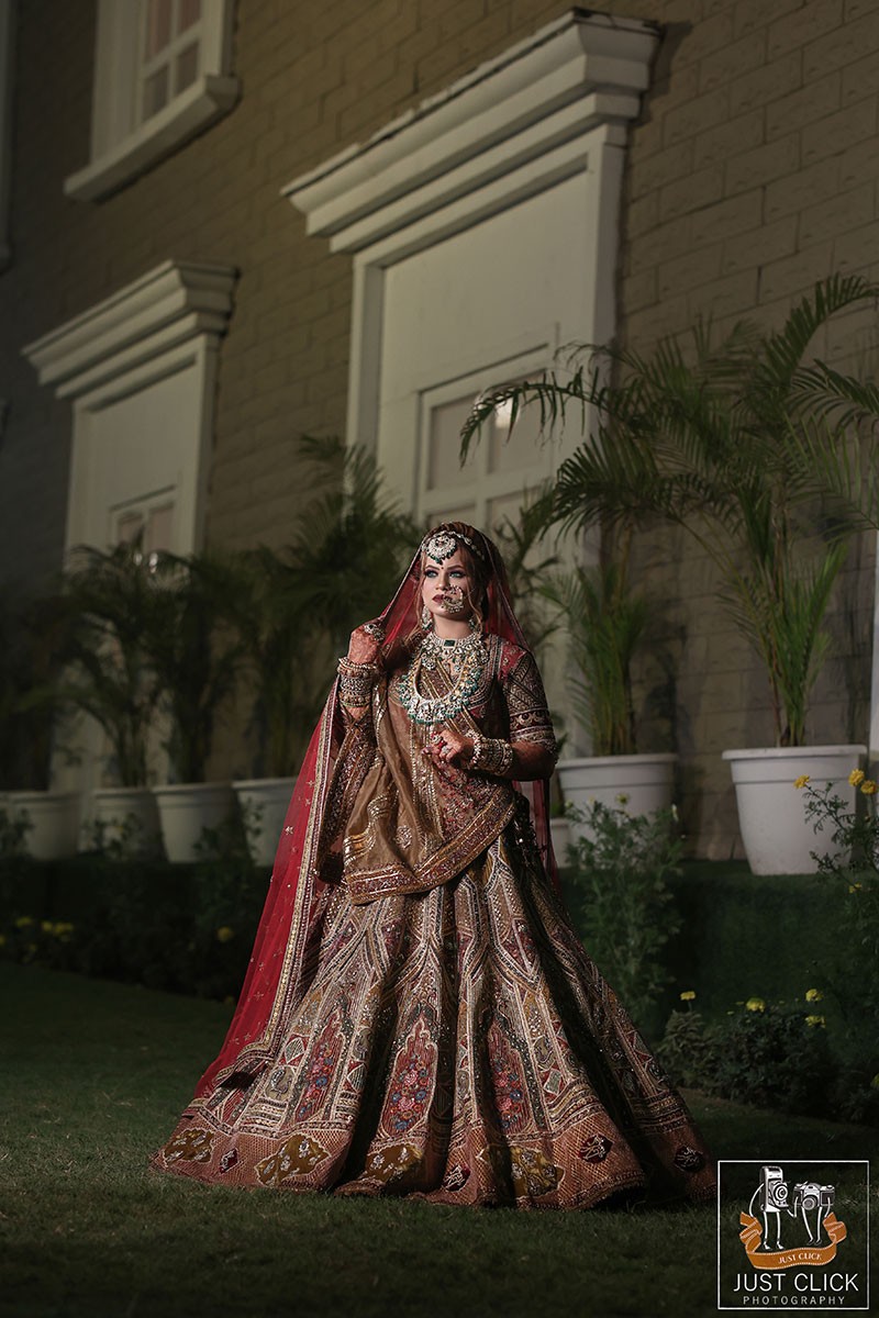 Bride posing solo outdoors in a red embellished outfit