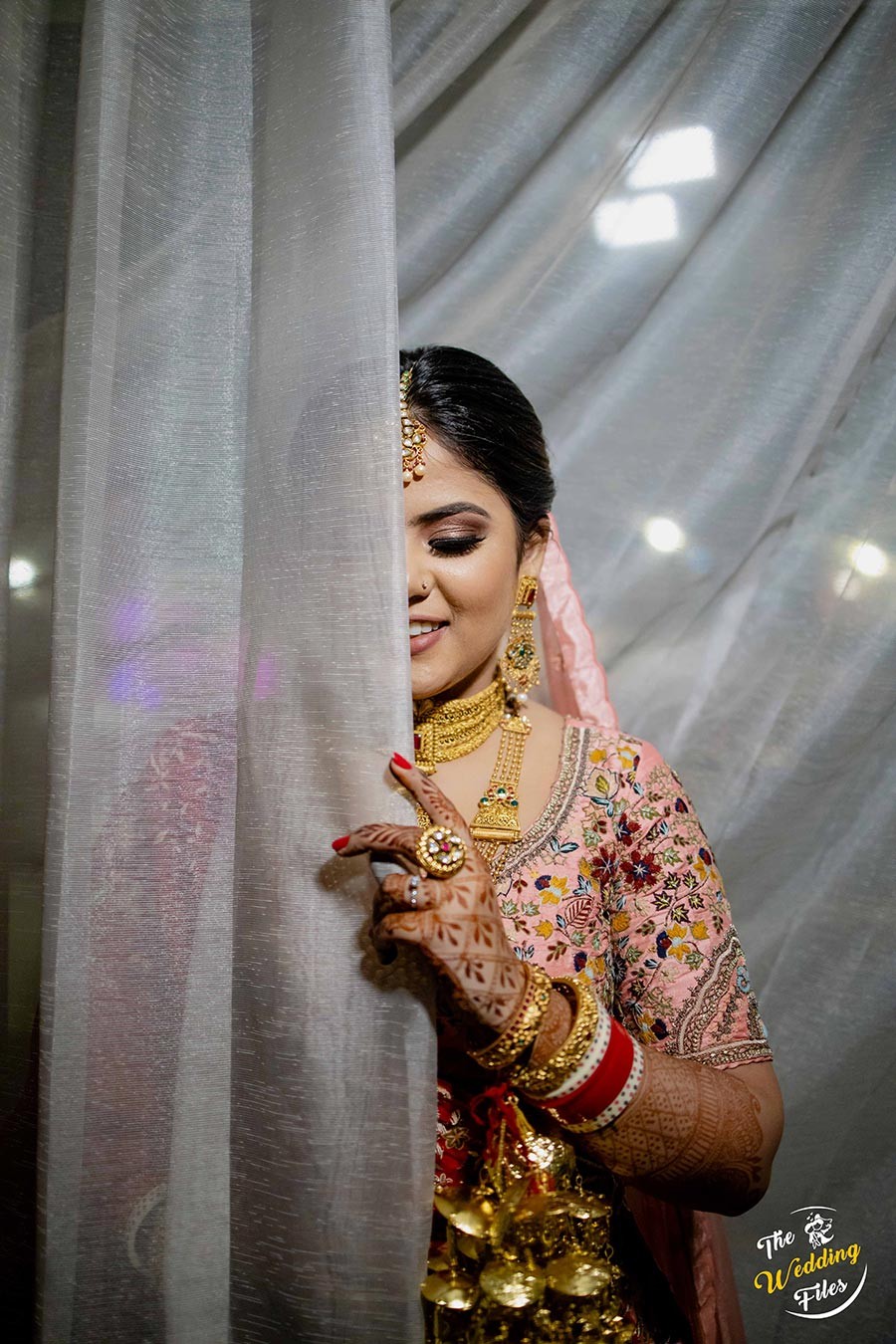 Bride Sanya in bridal finery beside draped curtains during her wedding portrait