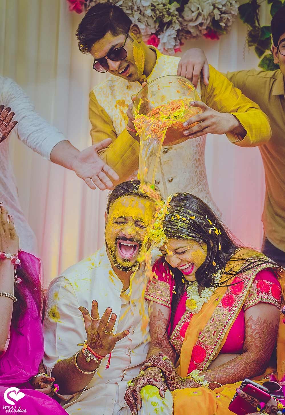 Guests in vibrant traditional attire amid marigold floral decor at Deepanshu and Sonali's wedding celebration