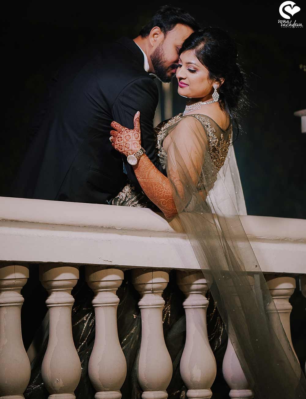 Deepanshu and Sonali embracing beside an ornate balcony railing during their wedding celebration