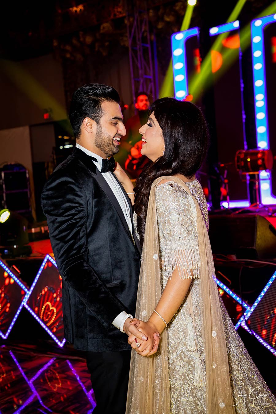 Vrinda and Mohit amid warm decorative lighting during their wedding