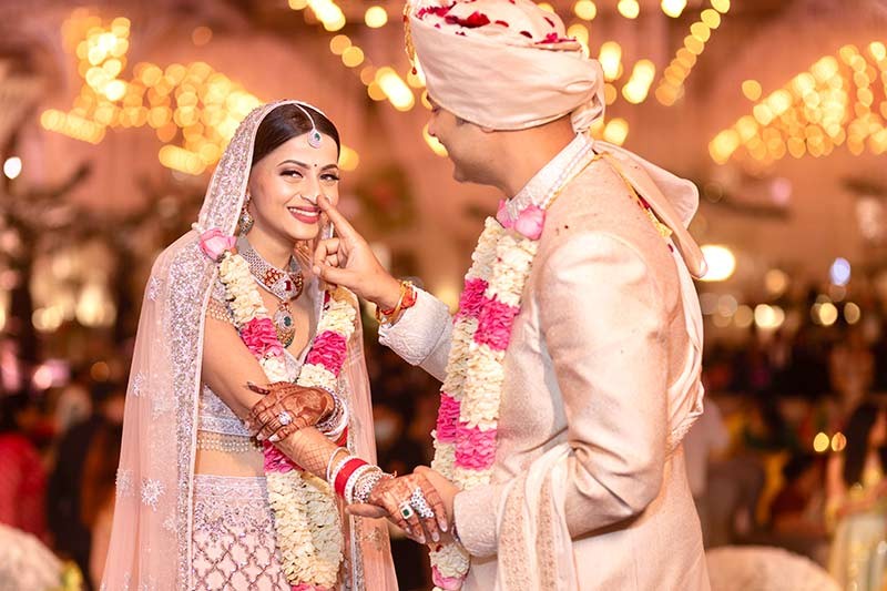 Bride and groom posing closely together under warm lighting
