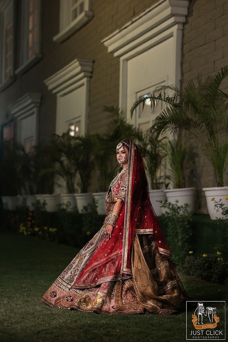 Bride posing solo outdoors in a red bridal outfit