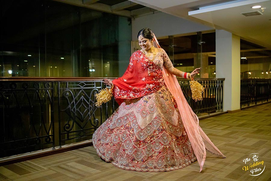 Bride Sanya in an ornate red bridal outfit posing during her wedding to Anish