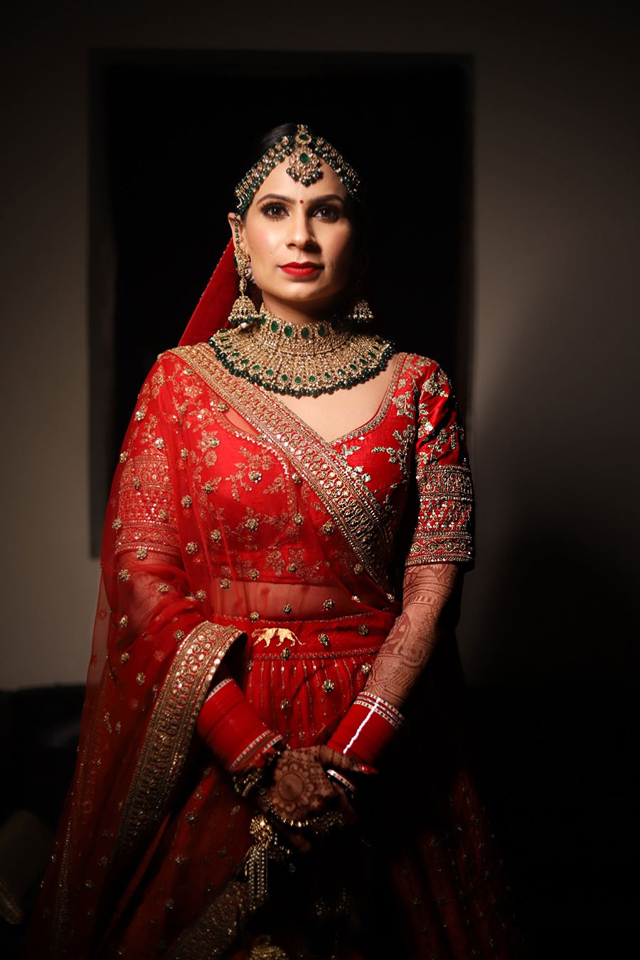 Portrait of Ayushi and Shashwat in red wedding attire at their celebration