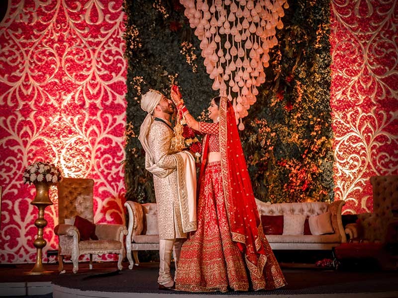 Priyansh and Priyanka in traditional attire amid red wedding decor