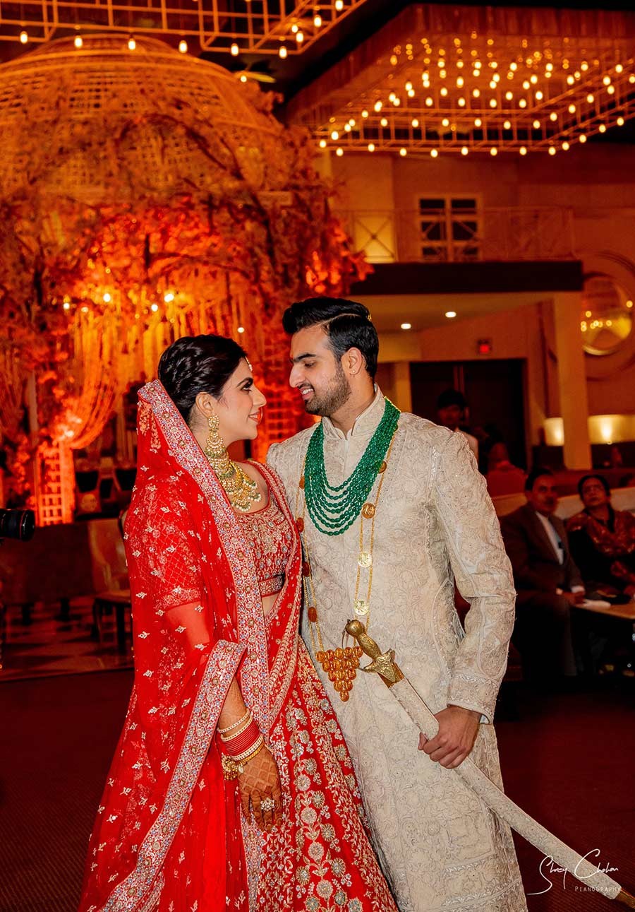 Bride and groom smiling closely together against a warm orange backdrop