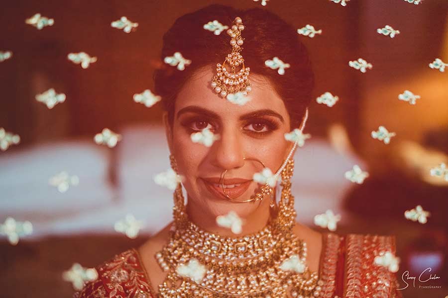 Close-up portrait of bride wearing ornate gold jewellery and a maang tikka