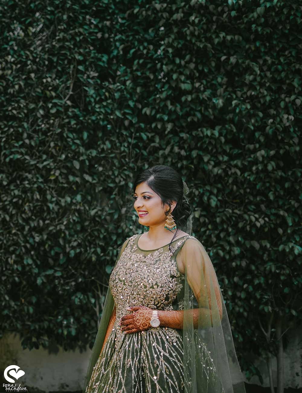 Bride Sonali seated gracefully against a green foliage backdrop during her wedding portrait