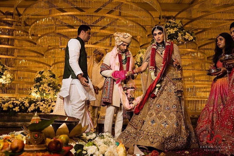 Bride and groom seated together in red and gold wedding attire