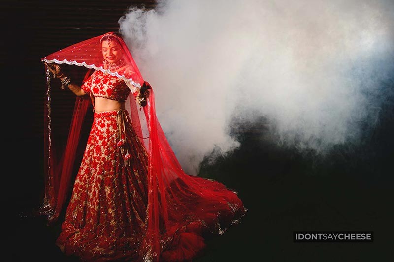 Bride walking in a red bridal outfit amid smoke effects