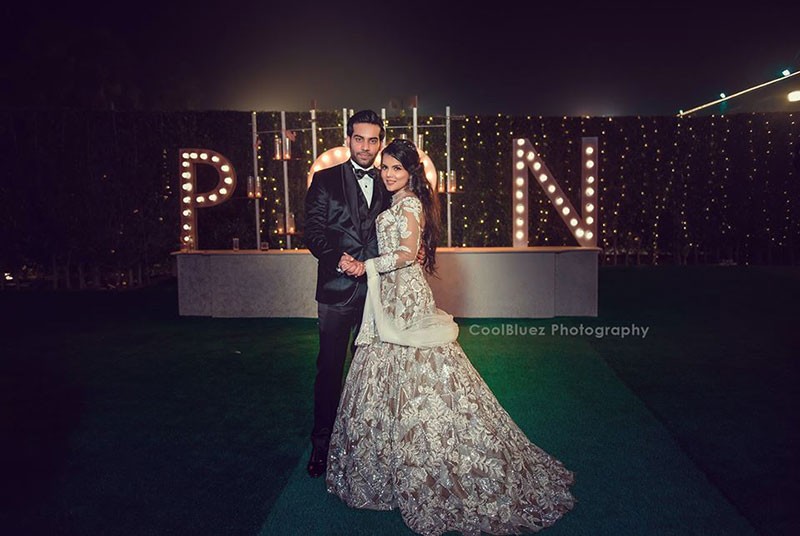 Bride Neha in a dramatic gown on stage at her reception