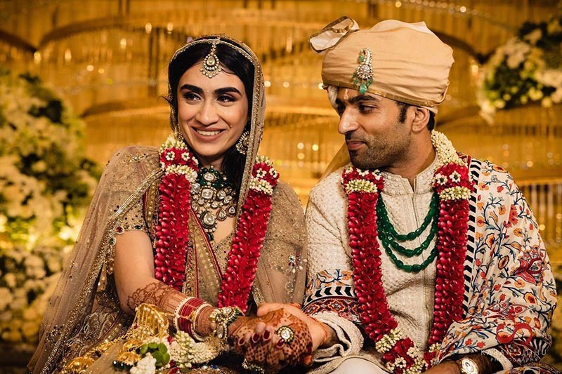 Close-up of bride and groom smiling together wearing garlands