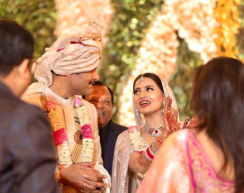 Bride and groom posing closely together against pink floral decor