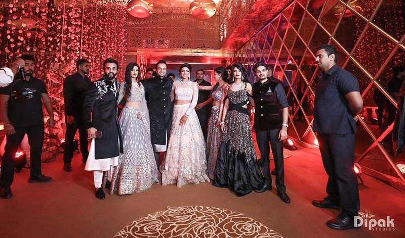 Shreejeet and Tanvi with guests amid festive red decor at their wedding