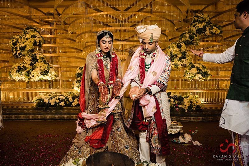 Bride and groom posing together in red and cream wedding attire