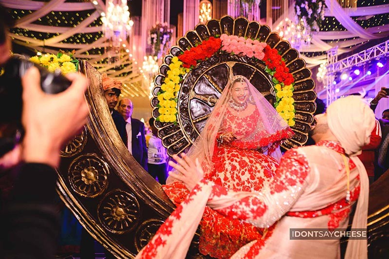 Bride and groom posing closely together wearing garlands