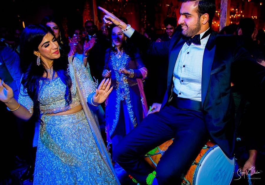 Bride and groom dancing on stage under colourful party lights