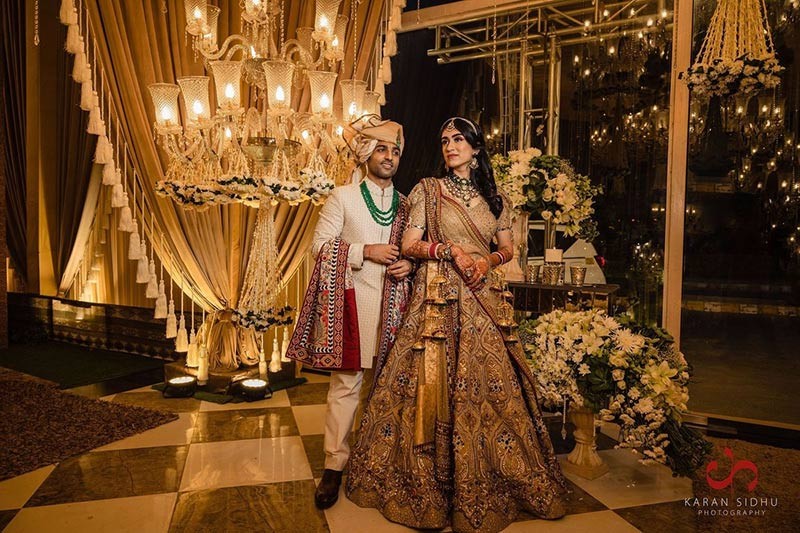 Bride and groom posing together in red and gold wedding attire