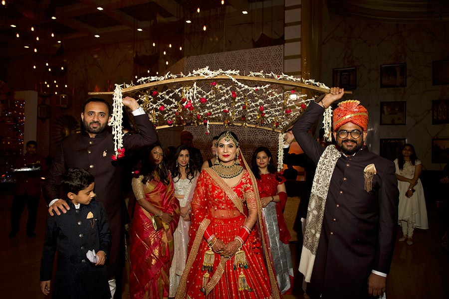 Ayushi and Shashwat beneath warm decorative lighting at their wedding