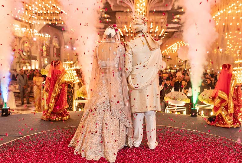 Bride posing solo in a pink bridal outfit at the decorated venue