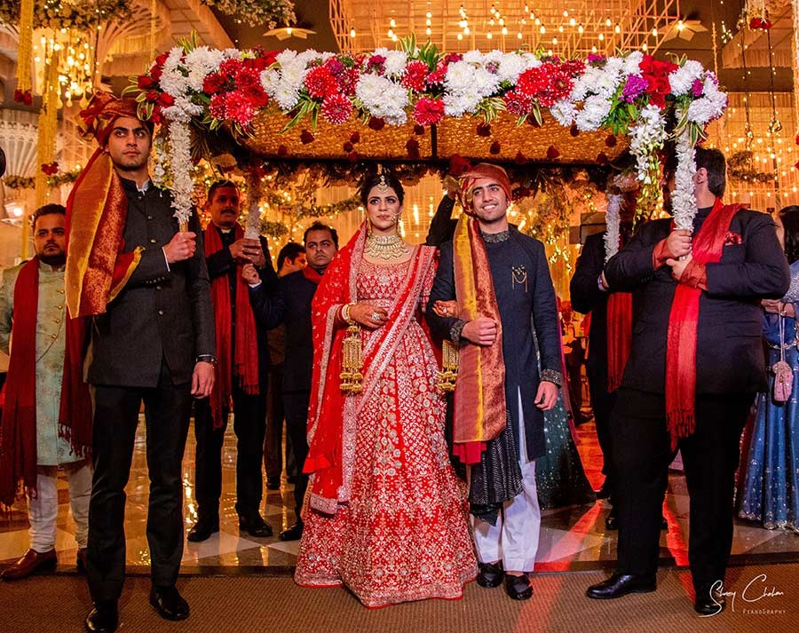 Bride and groom seated together at the mandap with red decor