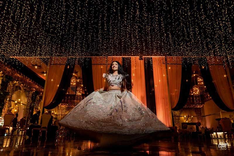 Bride posing solo in a gold embellished gown against a dark background