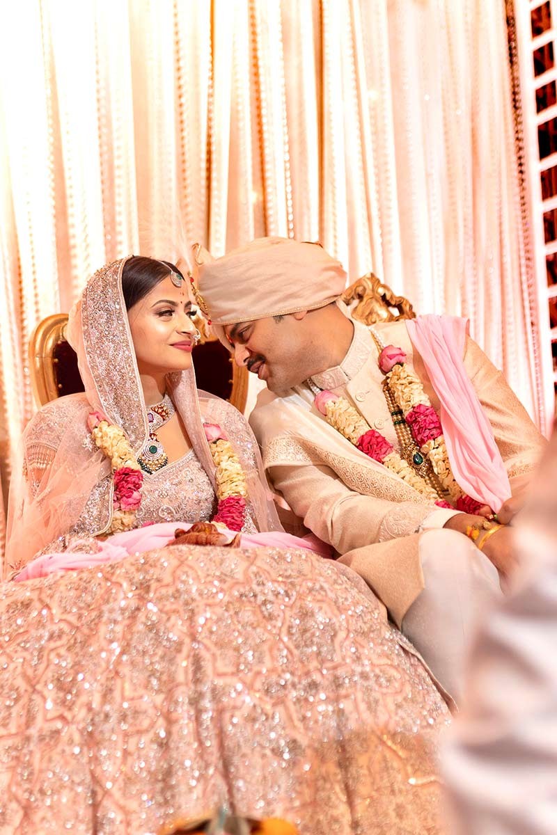 Bride and groom seated together at the floral decorated mandap