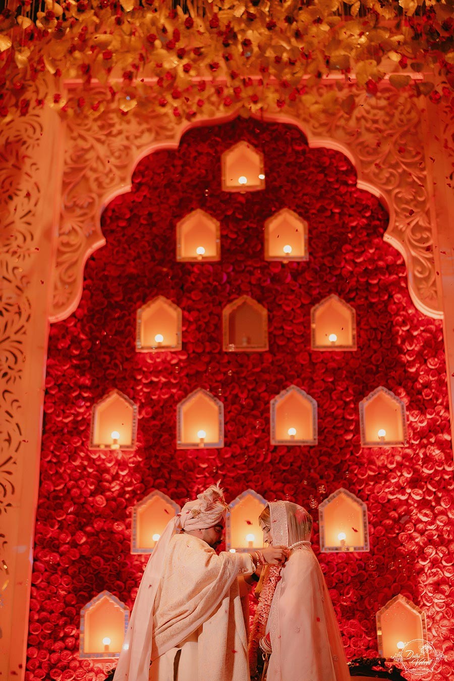 Richly lit red decor with rows of lamps at Prakriti and Sahil's wedding ceremony
