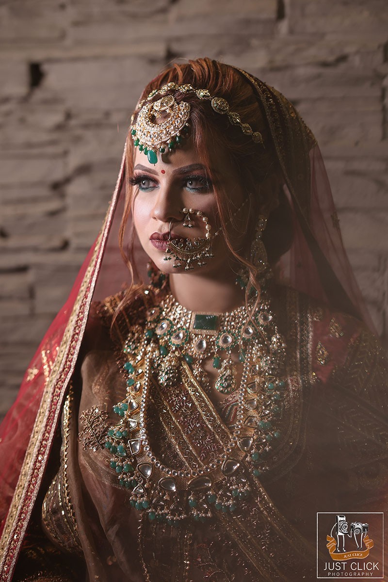 Bride posing solo outdoors in a red embellished outfit with a long train