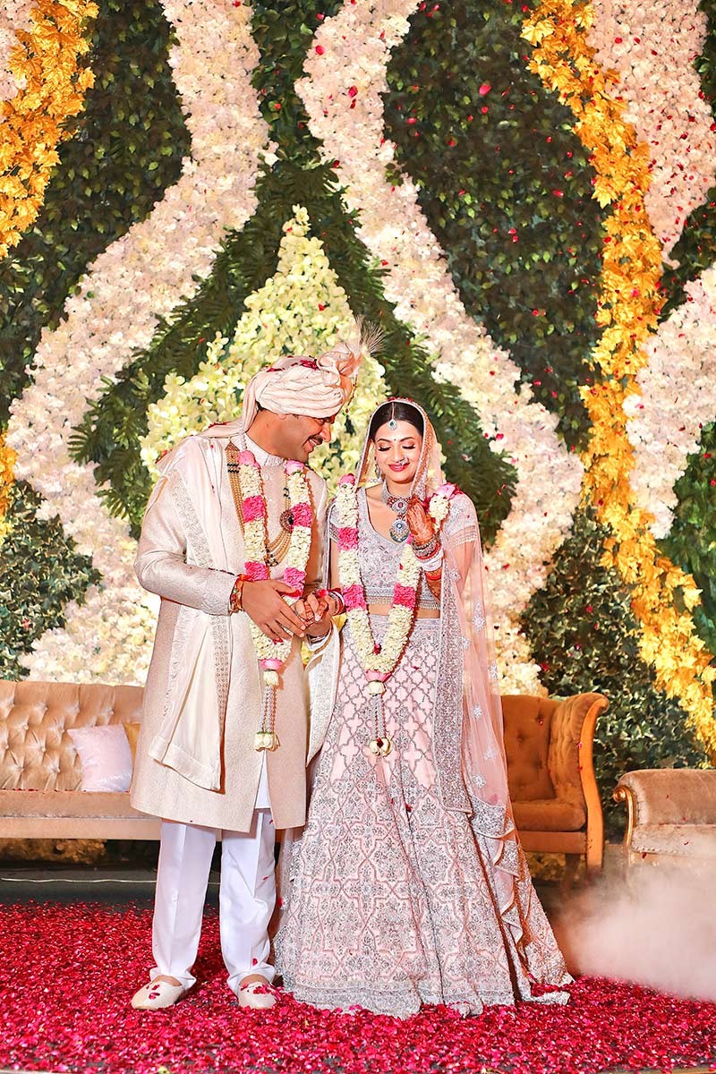 Bride and groom posing closely together against floral decor