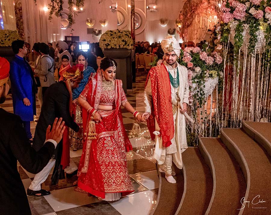 Bride and groom seated together during the wedding ceremony with red decor