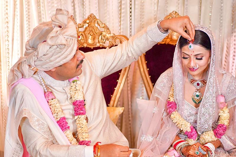 Bride and groom performing a ceremonial ritual amid floral decor
