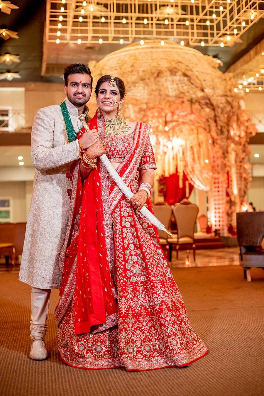 Bride in a red bridal outfit being assisted indoors before the ceremony