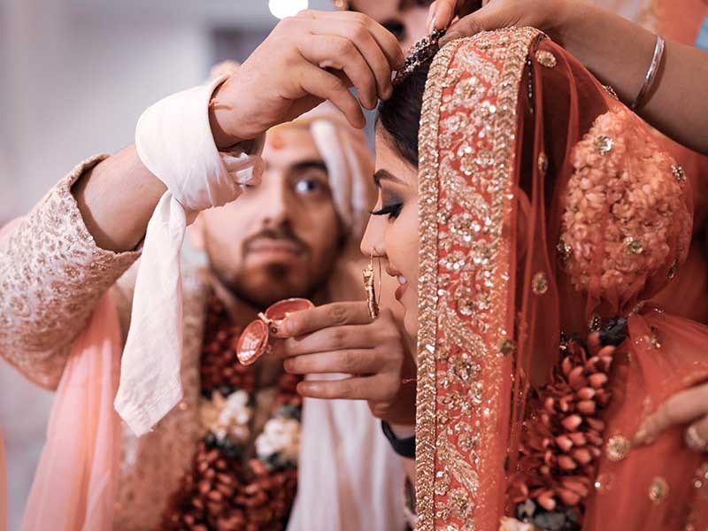 Priyansh and Priyanka embracing in warm pink lighting at their wedding