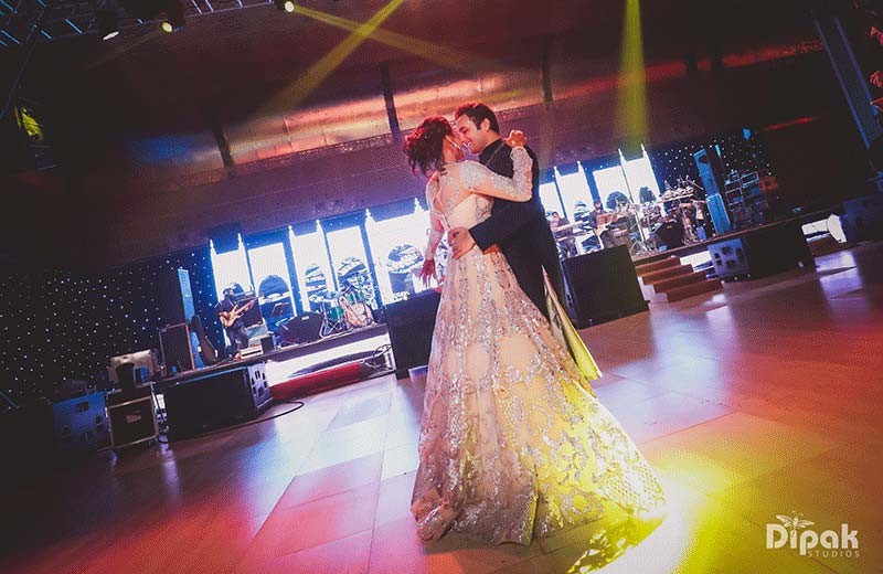 Shreejeet and Tanvi on stage under dramatic lighting at their wedding