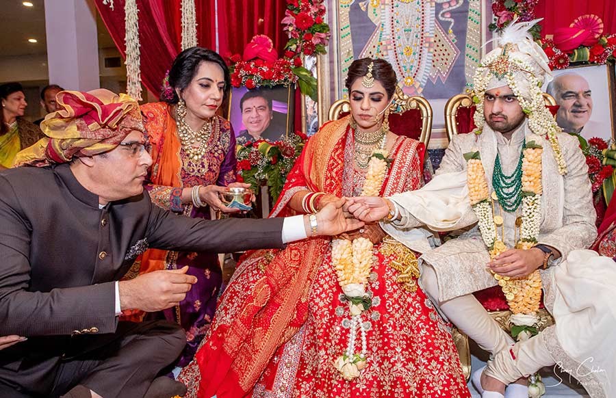 Bride and groom close together in traditional red and orange wedding attire