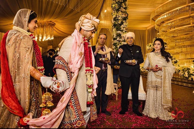 Bride and groom standing together in red and gold attire