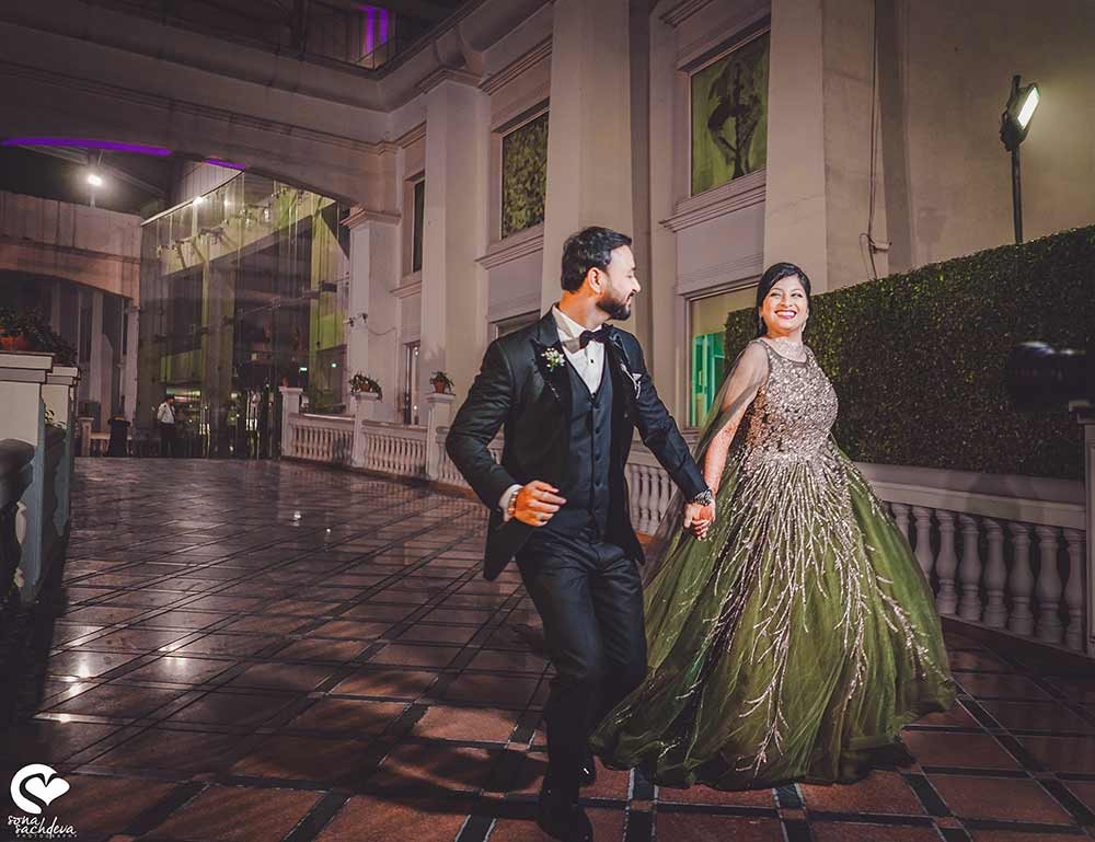 Deepanshu and Sonali on a floral-decorated stage with dramatic lighting during their wedding ceremony