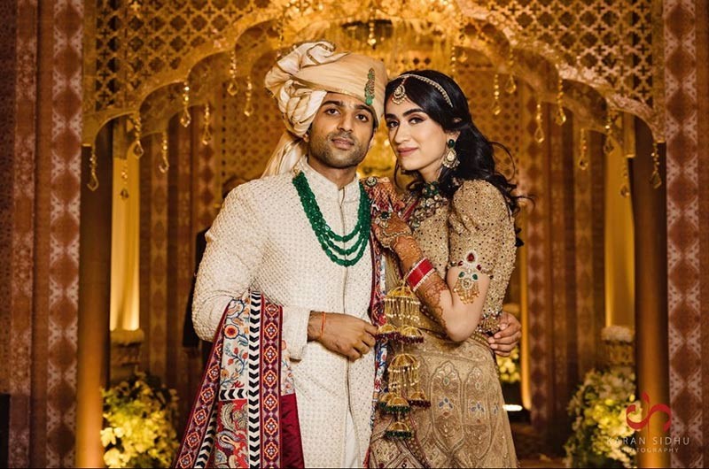 Bride and groom embracing closely in colourful wedding attire