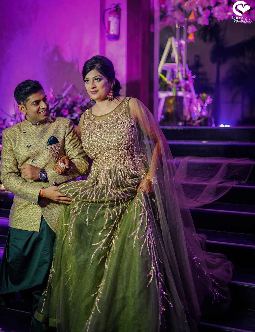 Deepanshu and Sonali with family in festive traditional attire under colorful lighting at their wedding
